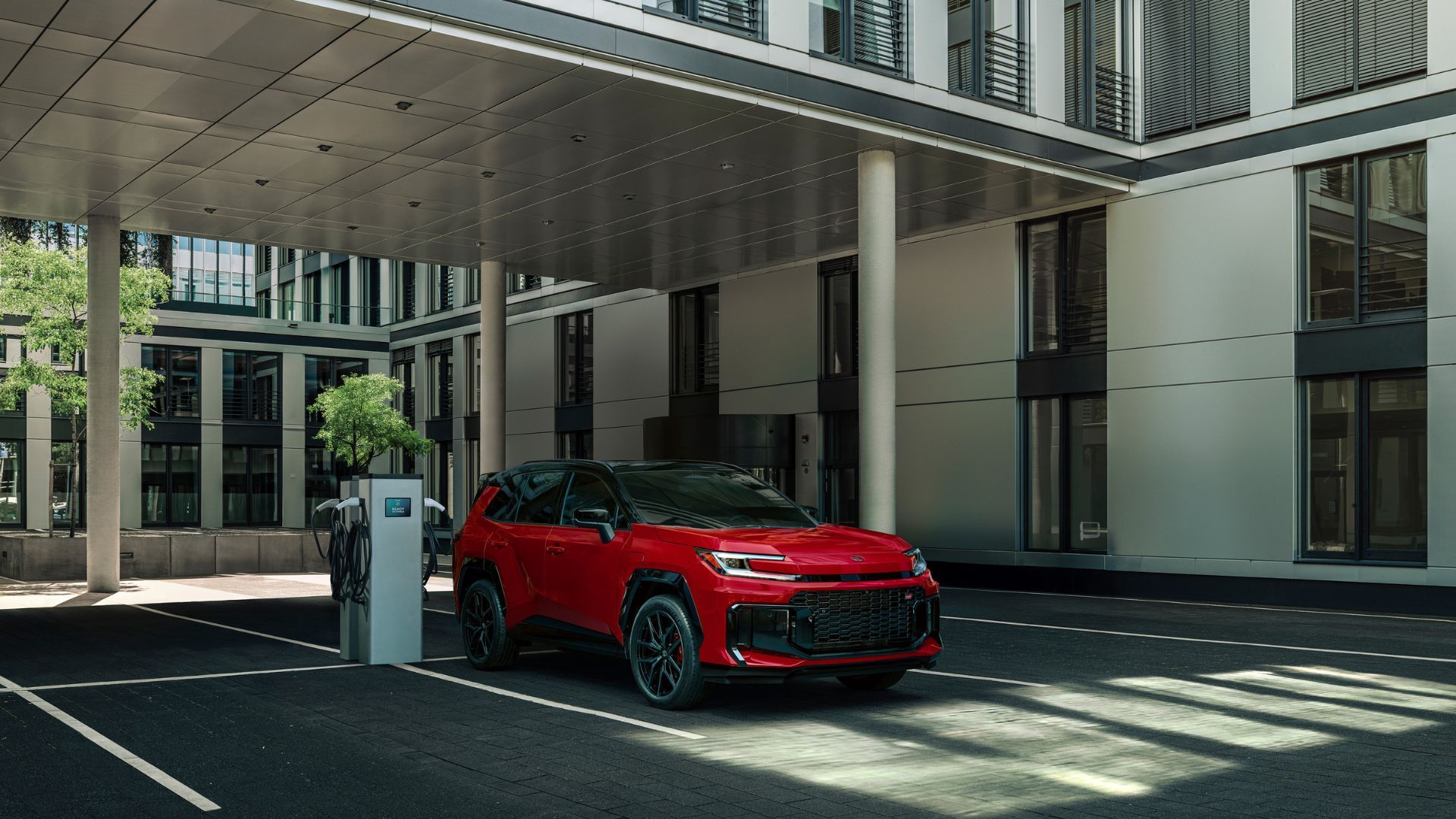 Static front 3/4 shot of a red 2026 Toyota RAV4 PHEV GR Sport charging.