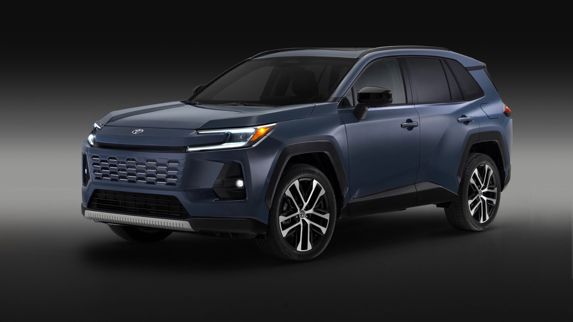 Static front 3/4 shot of a blue 2026 Toyota RAV4 Limited in a studio with a black and gray backdrop.