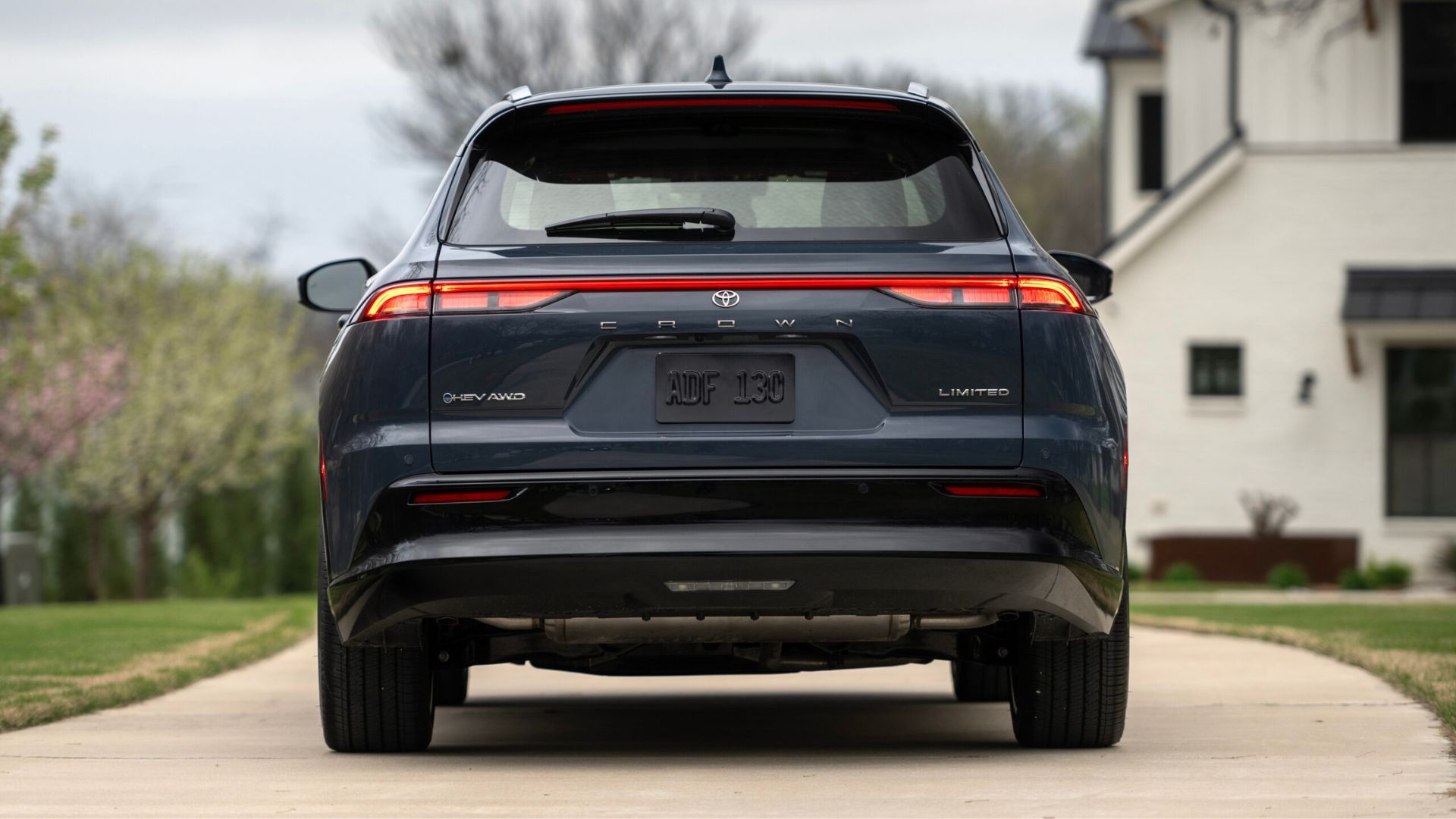 Static rear-end shot of a gray 2025 Toyota Crown Signia Limited parked on the driveway of a house.