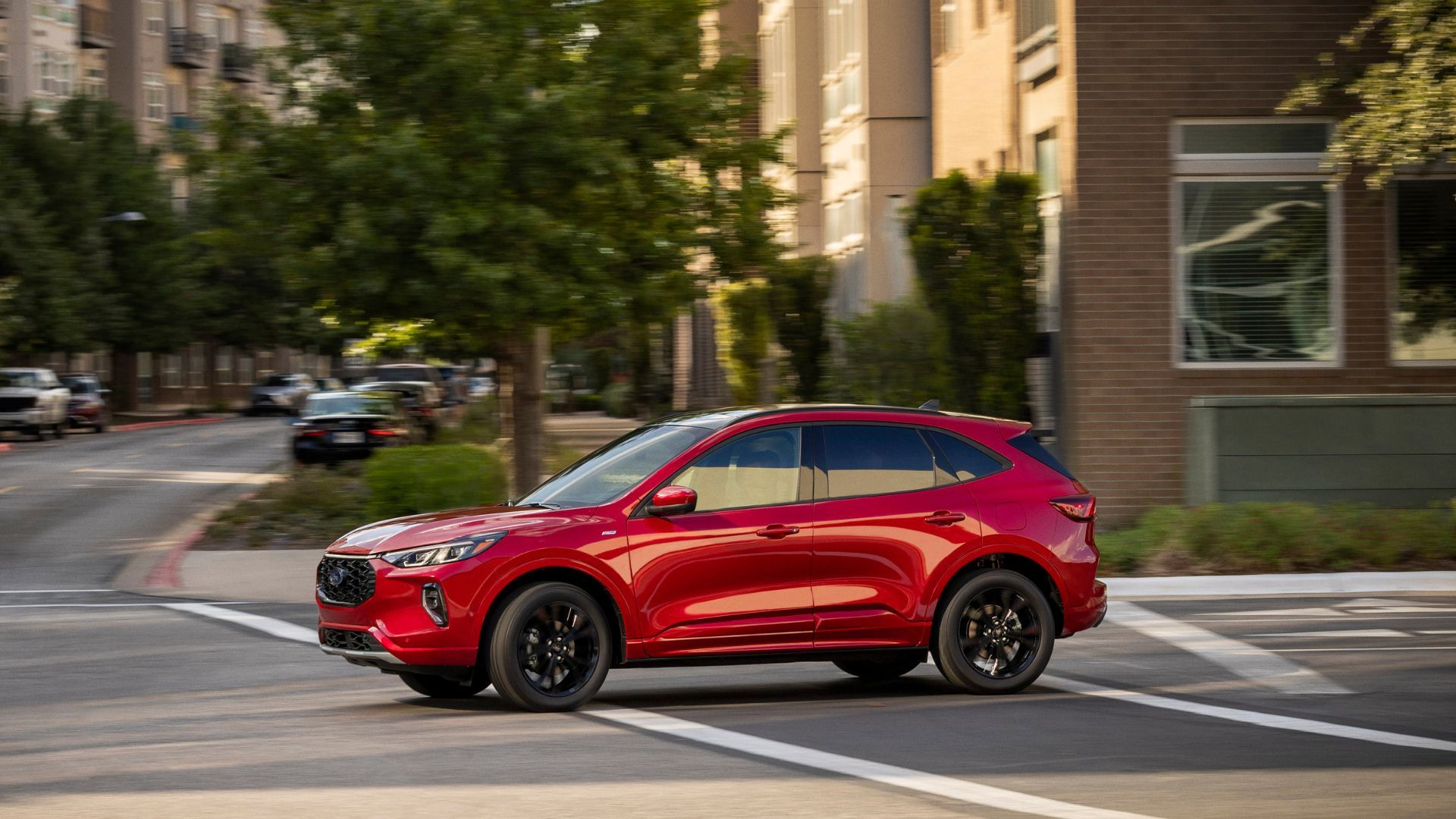 Dynamic side profile shot of a red 2023 Ford Escape ST-Line Elite driving through a city.
