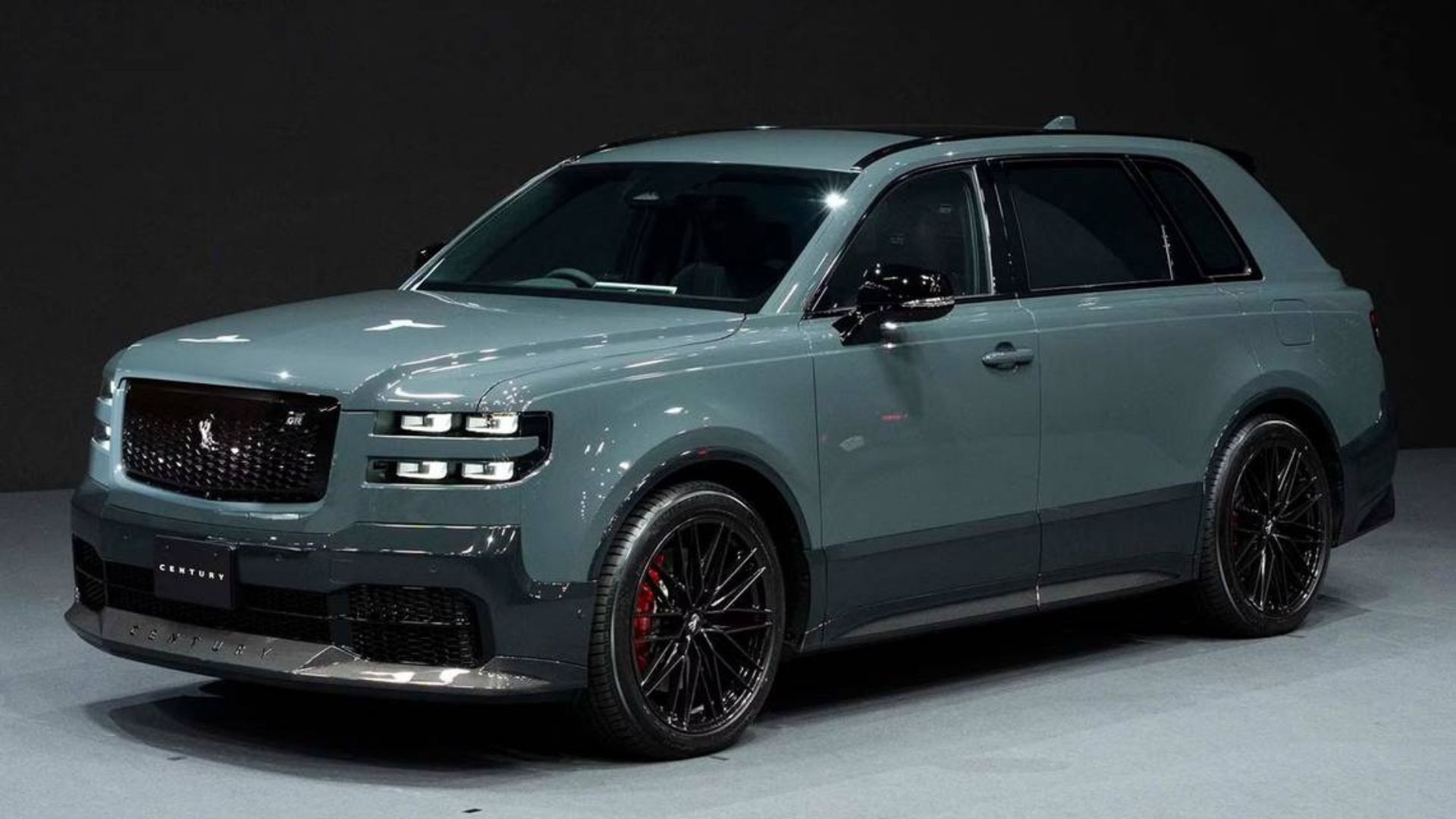 Front thgree-quarter view of a gray 2024 Toyota Century SUV on stage with a black background.