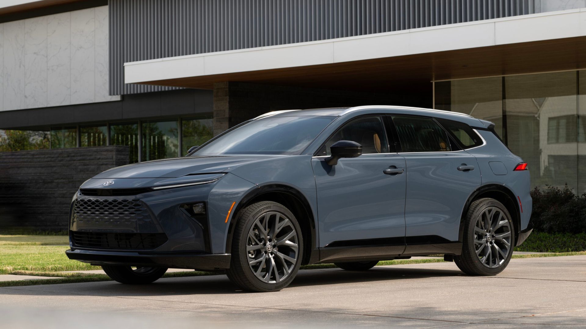 Static front 3/4 shot of a gray 2025 Toyota Crown Signia Limited parked outside of a modern building.