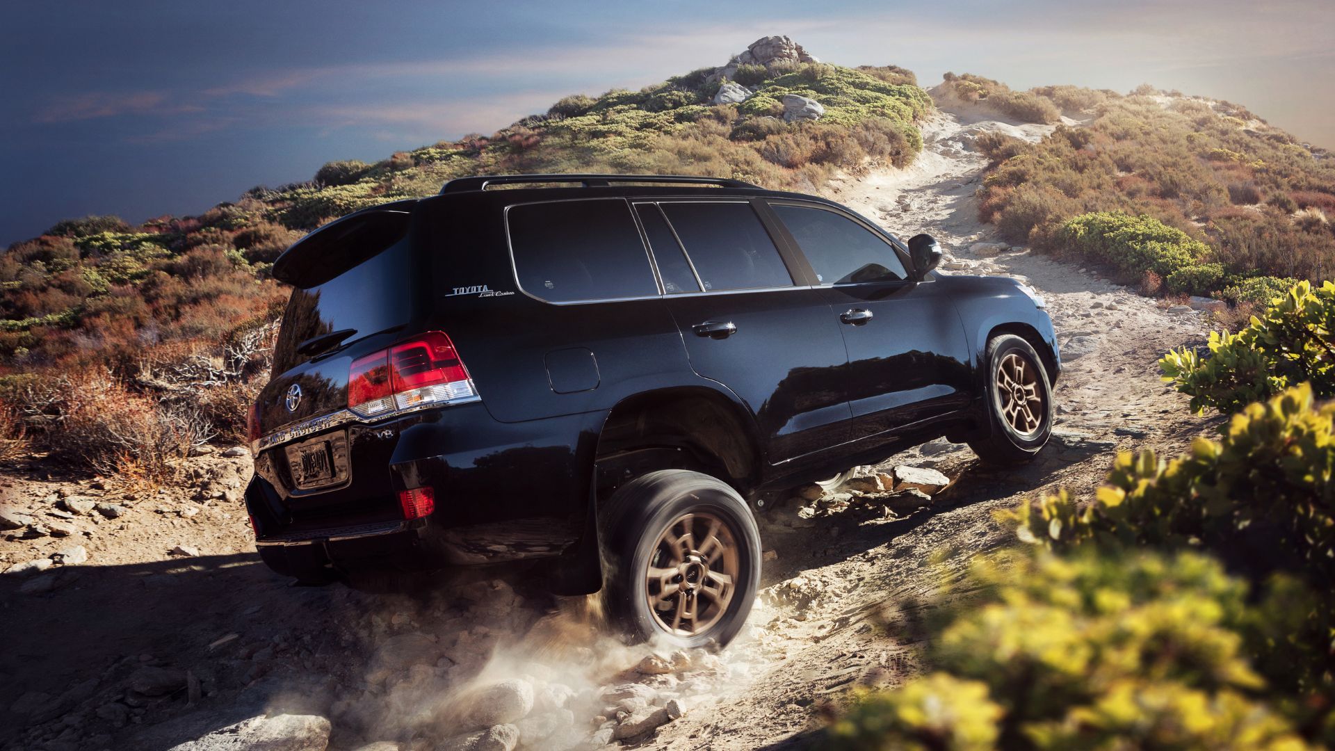 Dynamic rear 3/4 shot of a black 2021 Land Cruiser Heritage Edition off-roading.