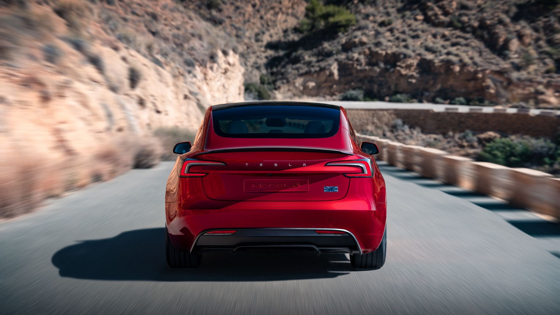Dynamic rear-end shot of a red Tesla Model 3 Performance.