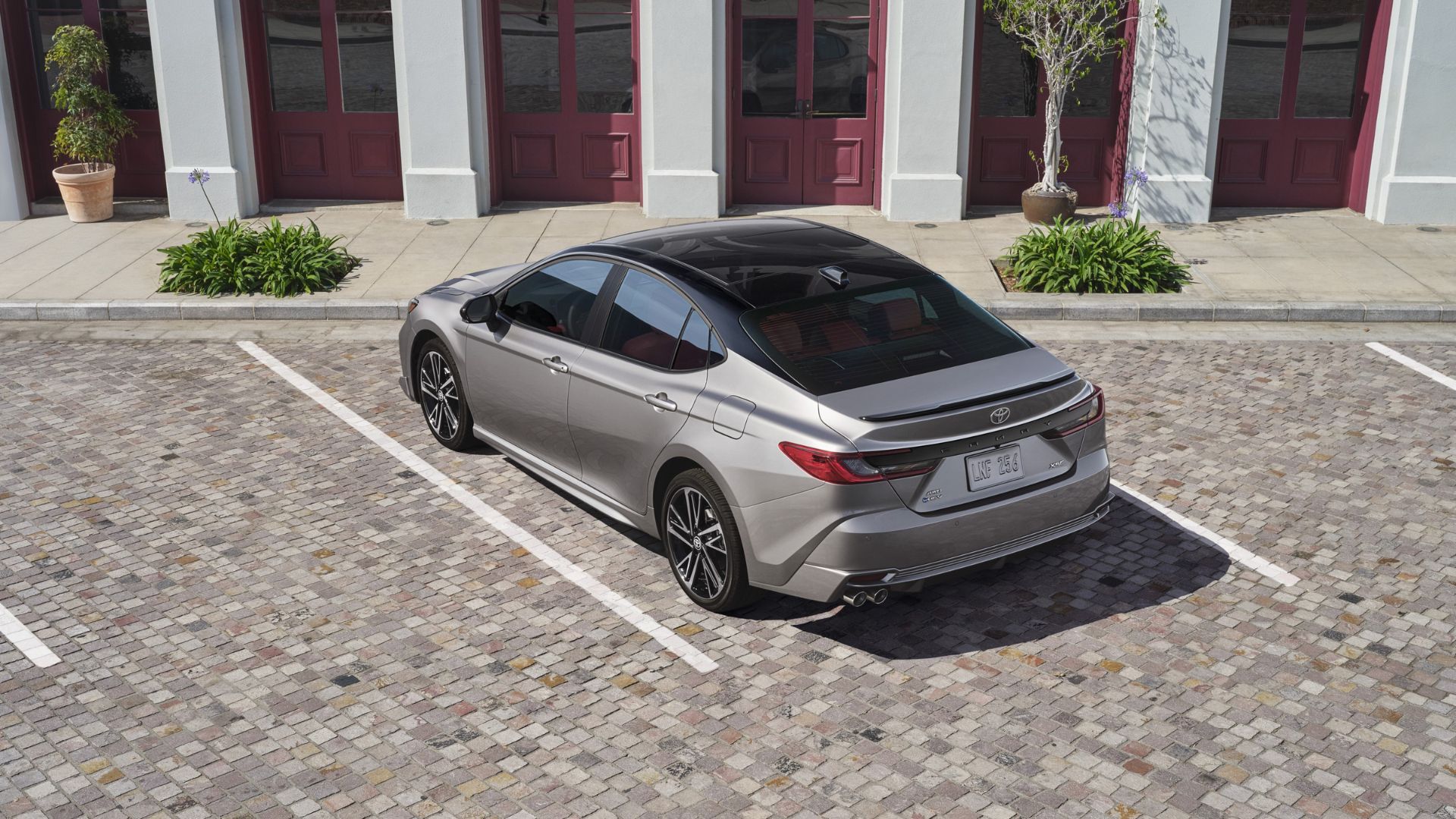 Rear 3/4 shot of a gray 2025 Toyota Camry XSE parked outside of a building.