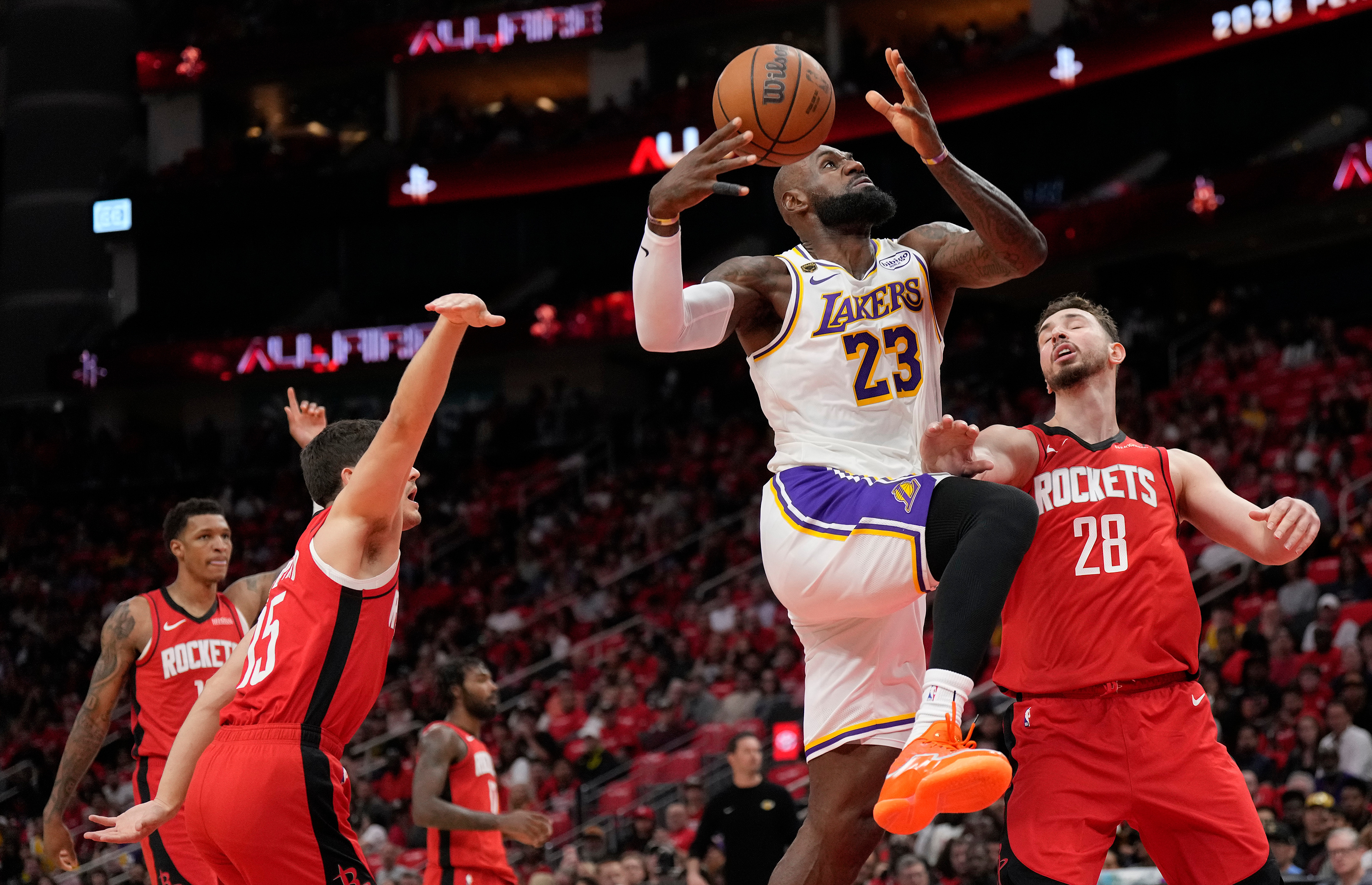 LeBron James goes to the basket against Reed Sheppard and Alperen Sengun during an NBA playoff game.