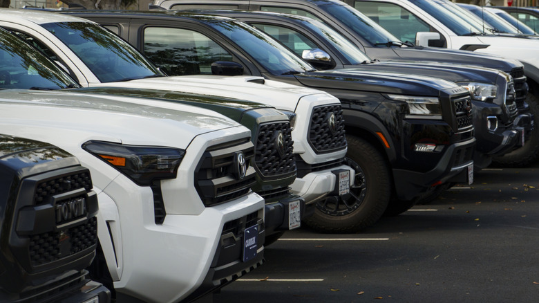 A line of used pickup trucks parked on a CarMax lot.